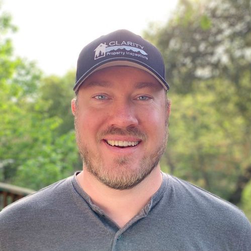 A man wearing a hat and a gray shirt is smiling for the camera.