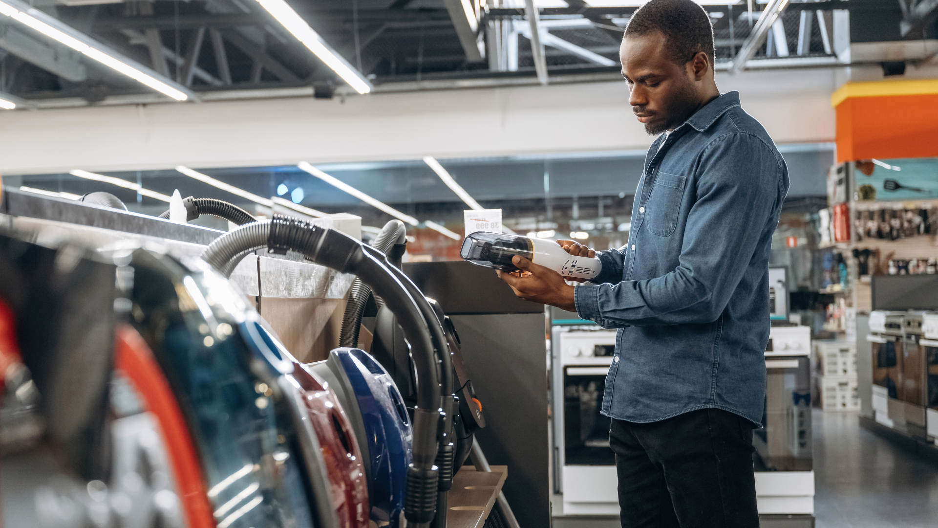 Vacuum cleaners displayed on a wall in a store. Various models and brands are visible.