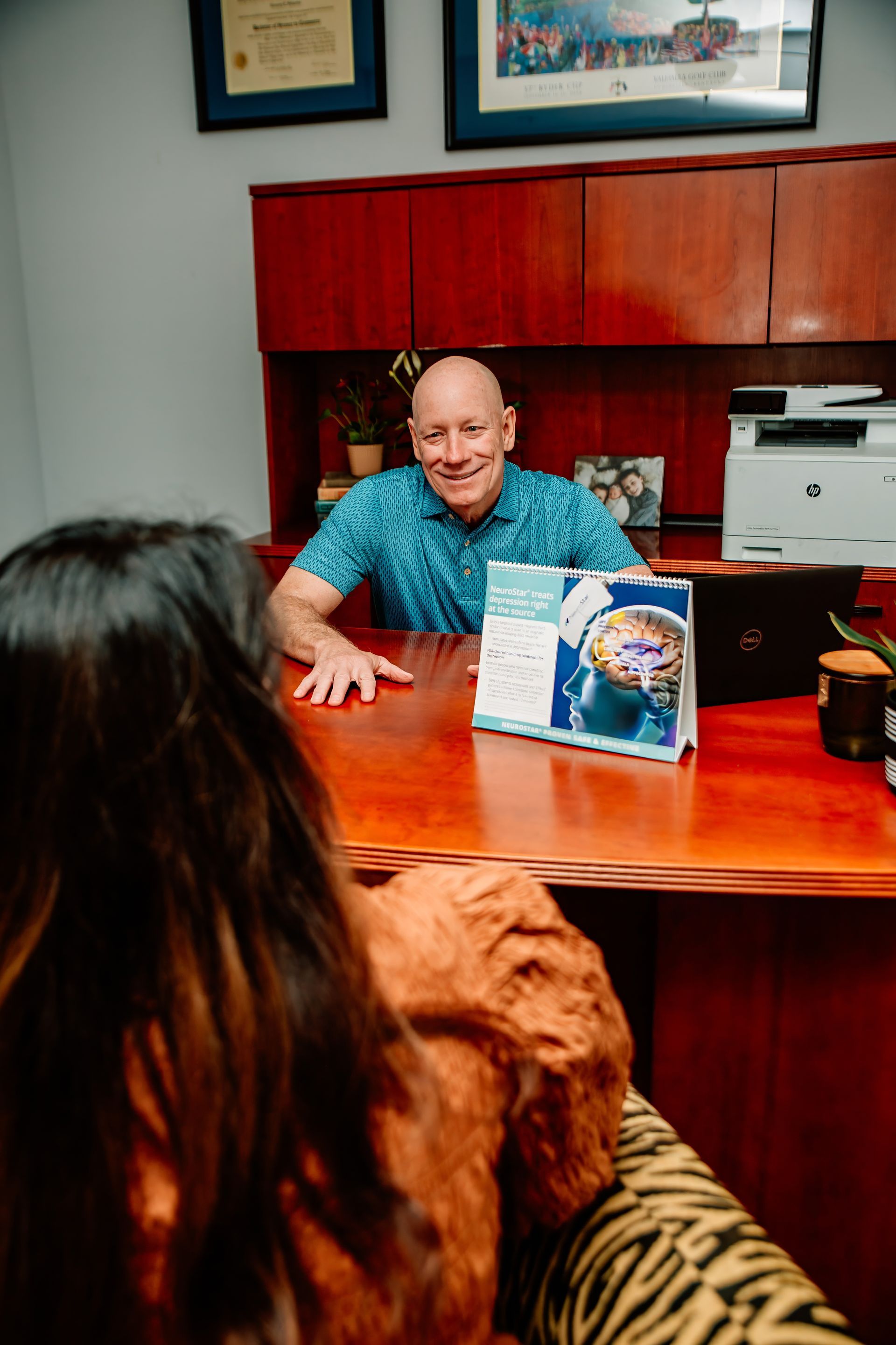 A man is sitting at a desk talking to a woman.