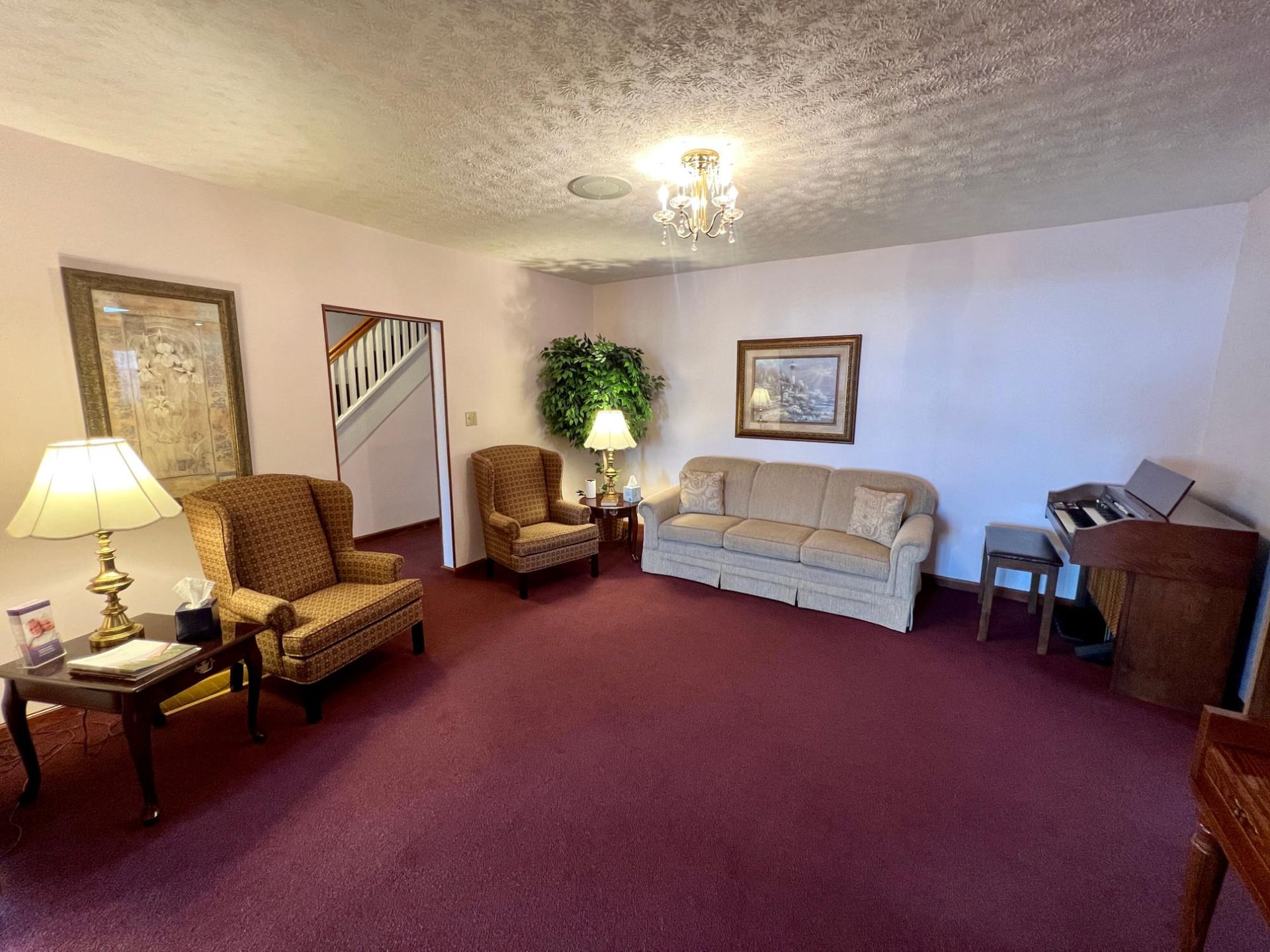 A living room with a couch , chairs , lamps and a piano.