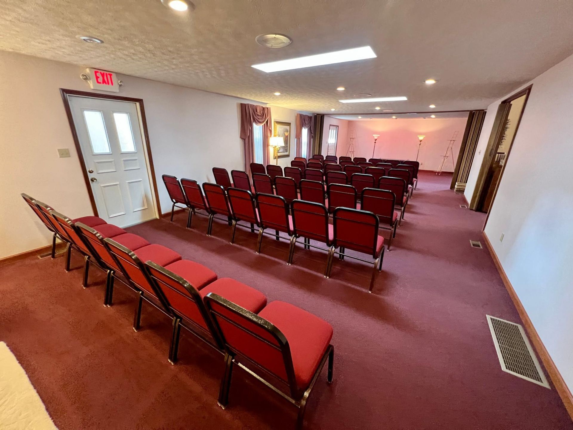 A row of red chairs in a room with a red carpet.