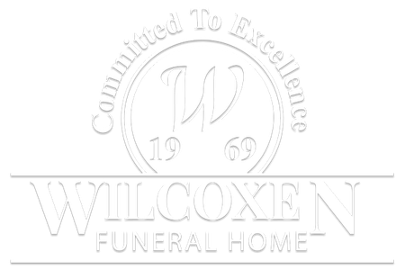 The logo for wilcoxen funeral home is white on a white background.