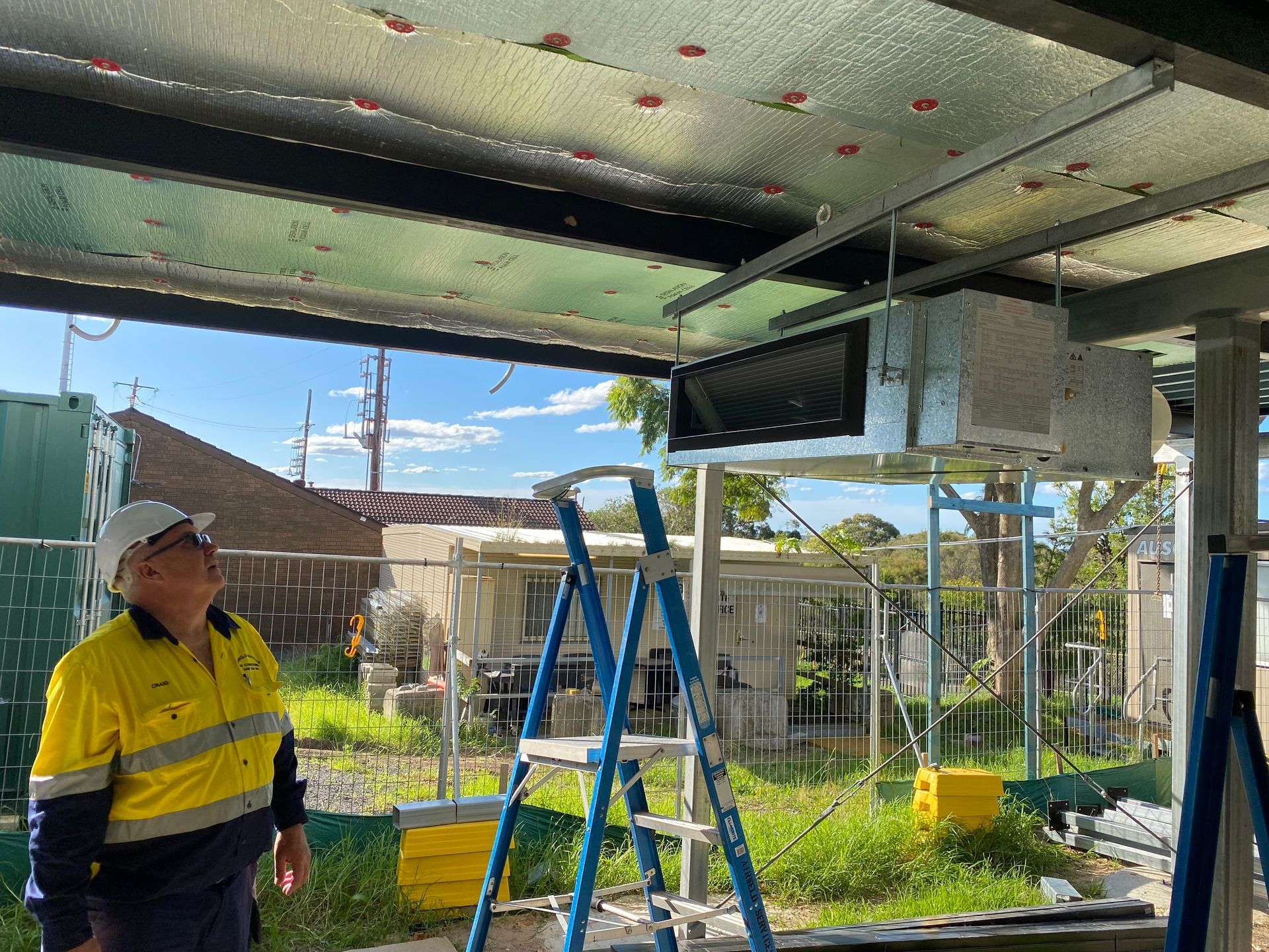 Construction worker looks up at installed HVAC unit under a building's exposed ceiling. — Airweld Services Pty Ltd in Shellharbour, NSW