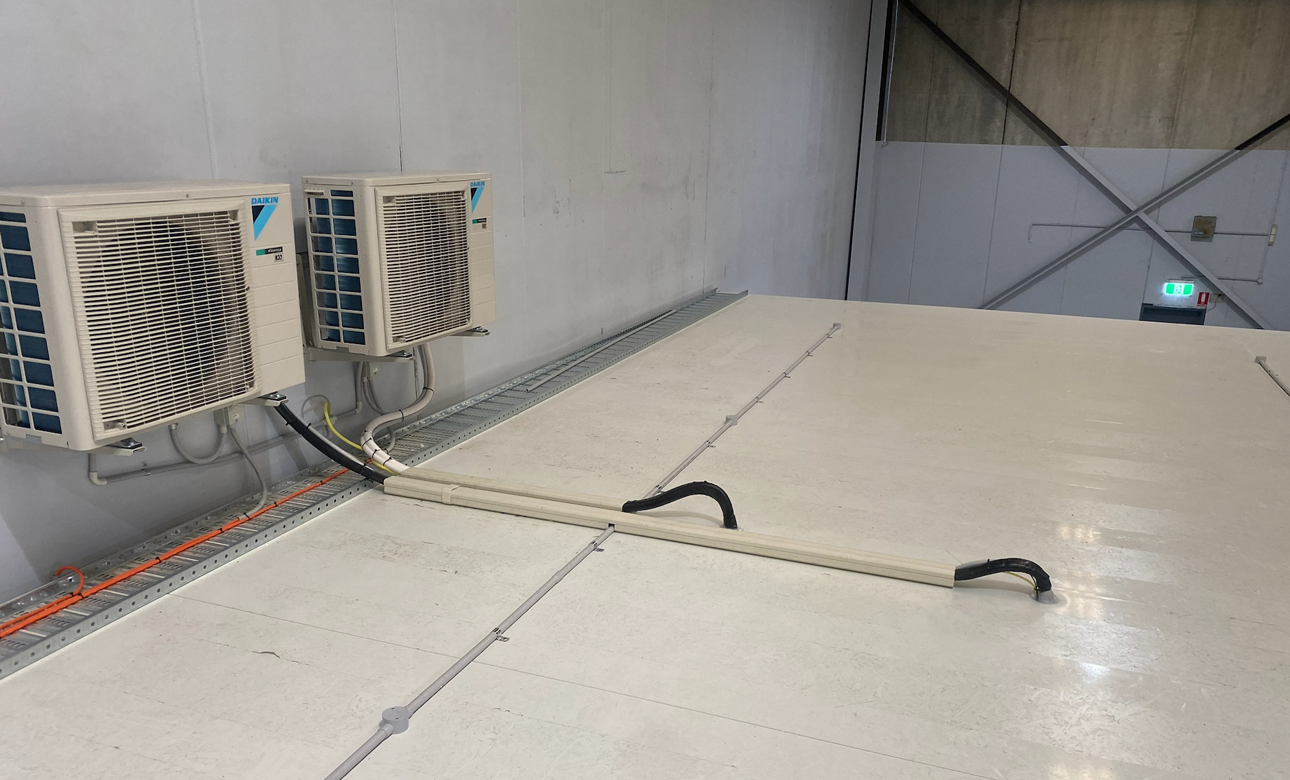 Two air conditioning units mounted on a white wall above a gray, industrial floor  — Airweld Services Pty Ltd in Shellharbour, NSW