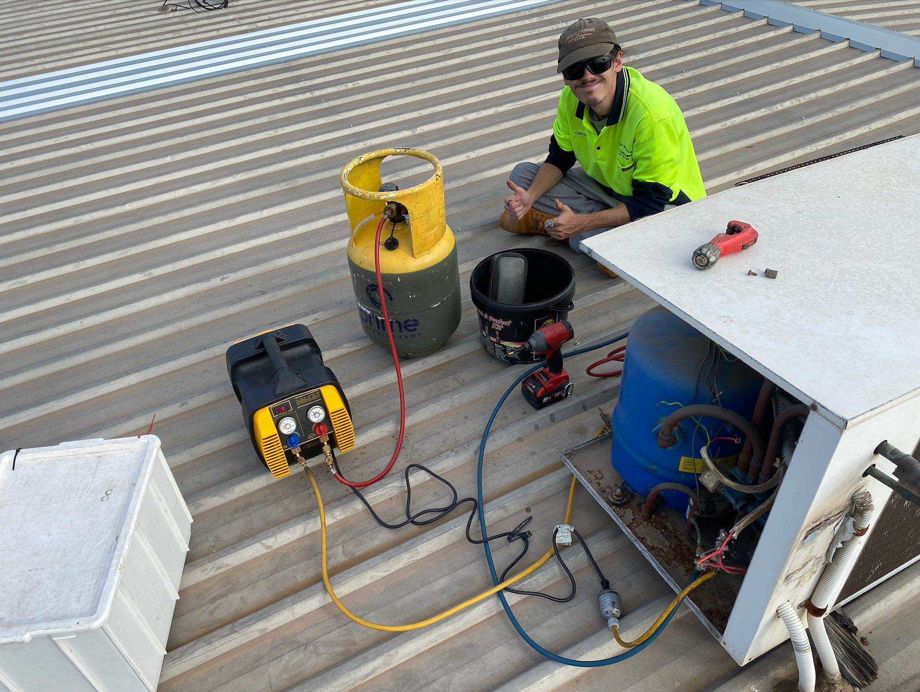 HVAC technician on a roof working on an AC unit, surrounded by tools and equipment — Airweld Services Pty Ltd in Wollongong, NSW