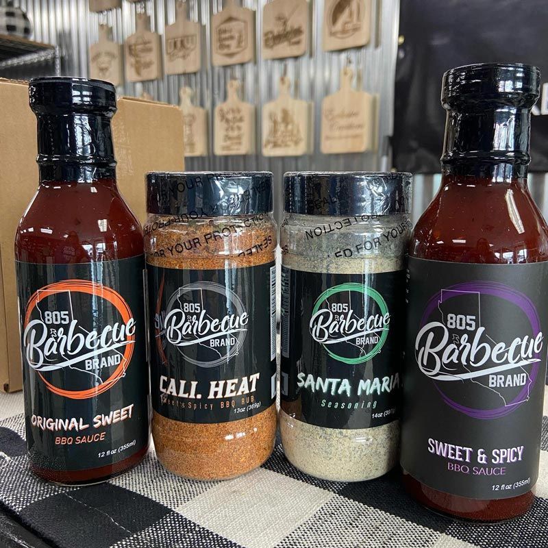 Four bottles of barbecue sauce and seasoning are sitting on a table.