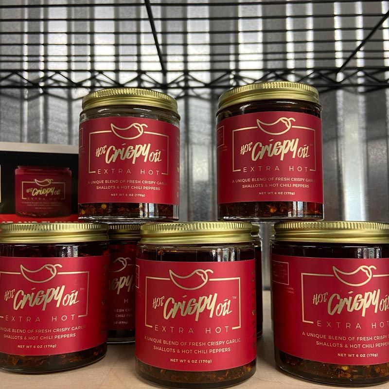 Several jars of hot crispy oil are lined up on a shelf