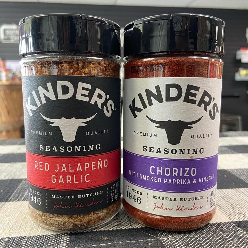 Two jars of kinder 's seasoning are sitting on a table.