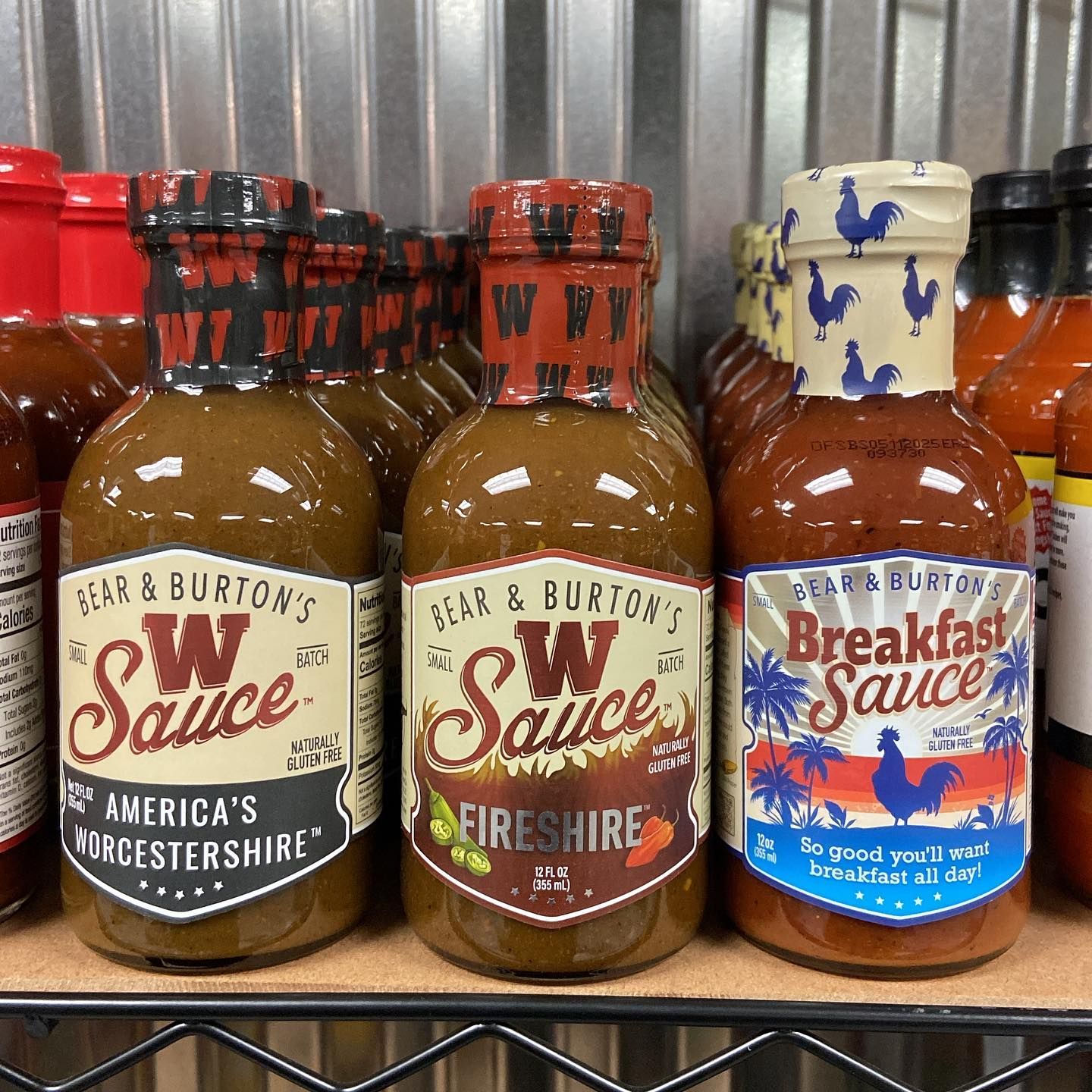 Three bottles of w sauce are lined up on a shelf
