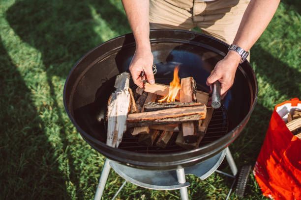 A person is putting wood on a grill.