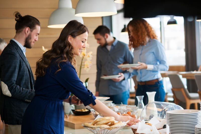 A woman is serving food to a group of people at a buffet.