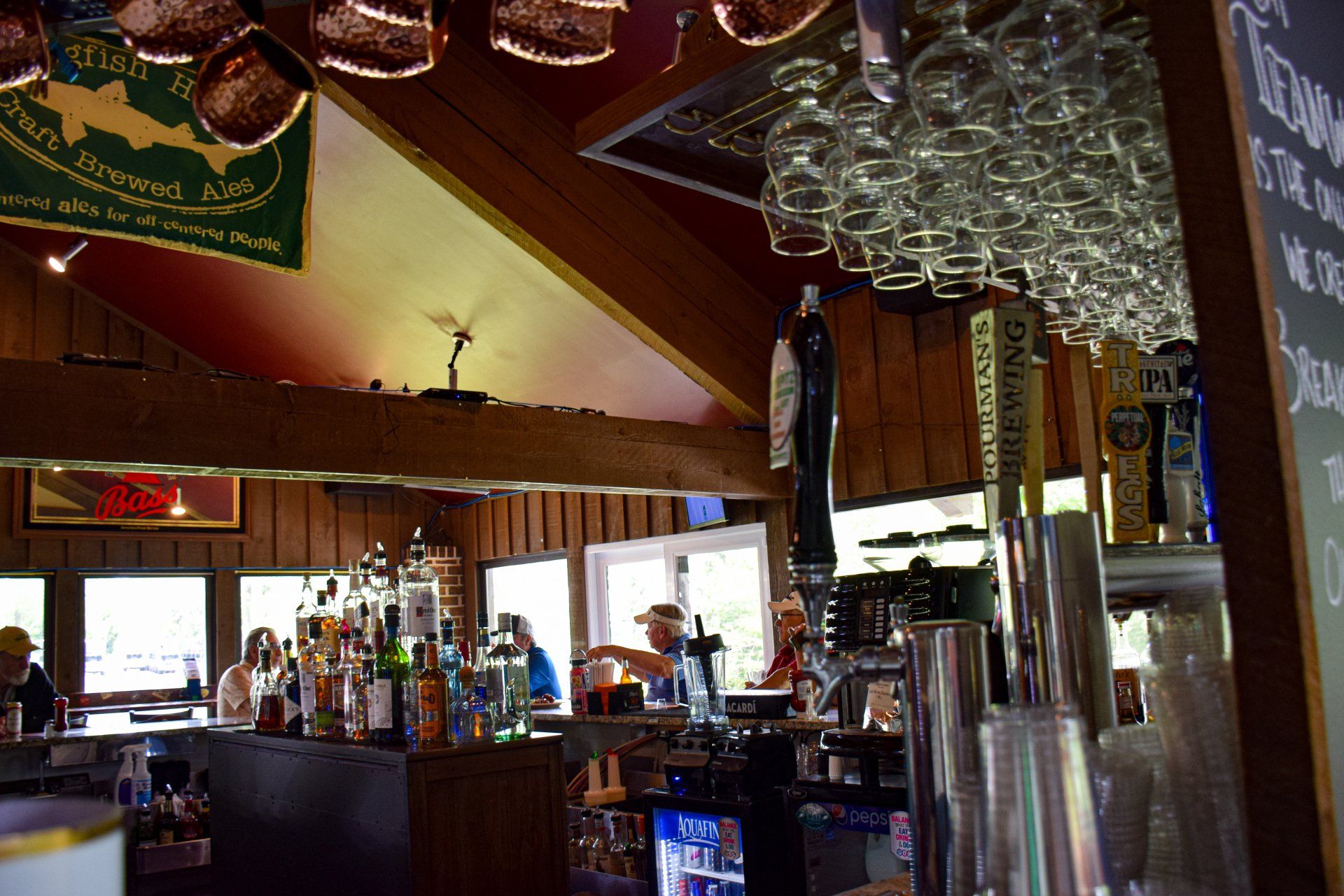 A bar with a lot of glasses hanging from the ceiling