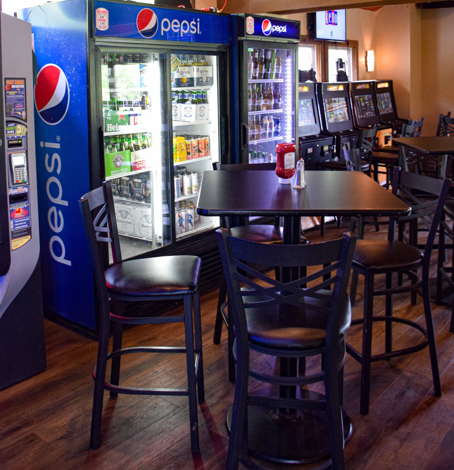 A pepsi fridge in a restaurant with tables and chairs