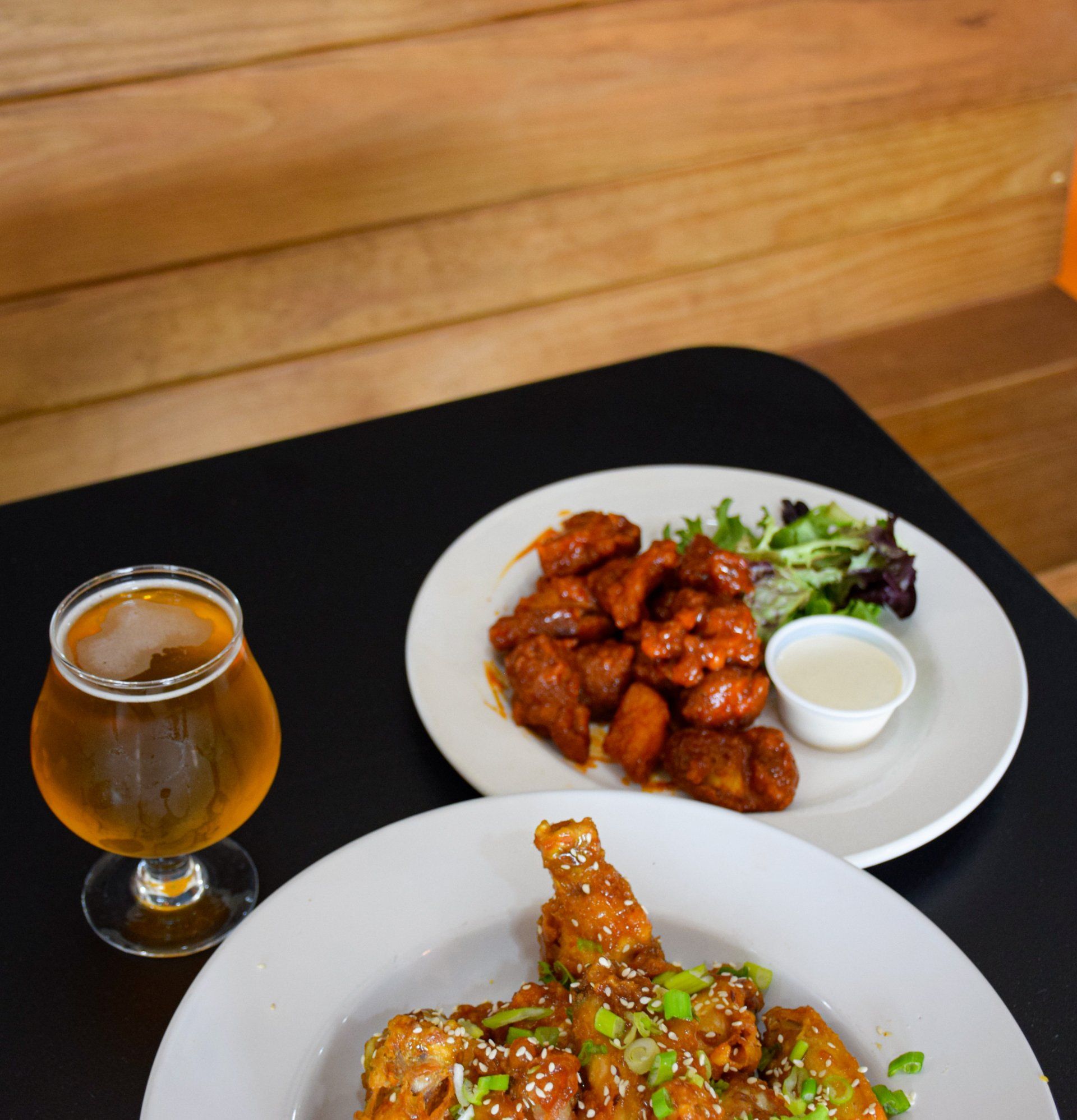 Two plates of food and a glass of beer on a table