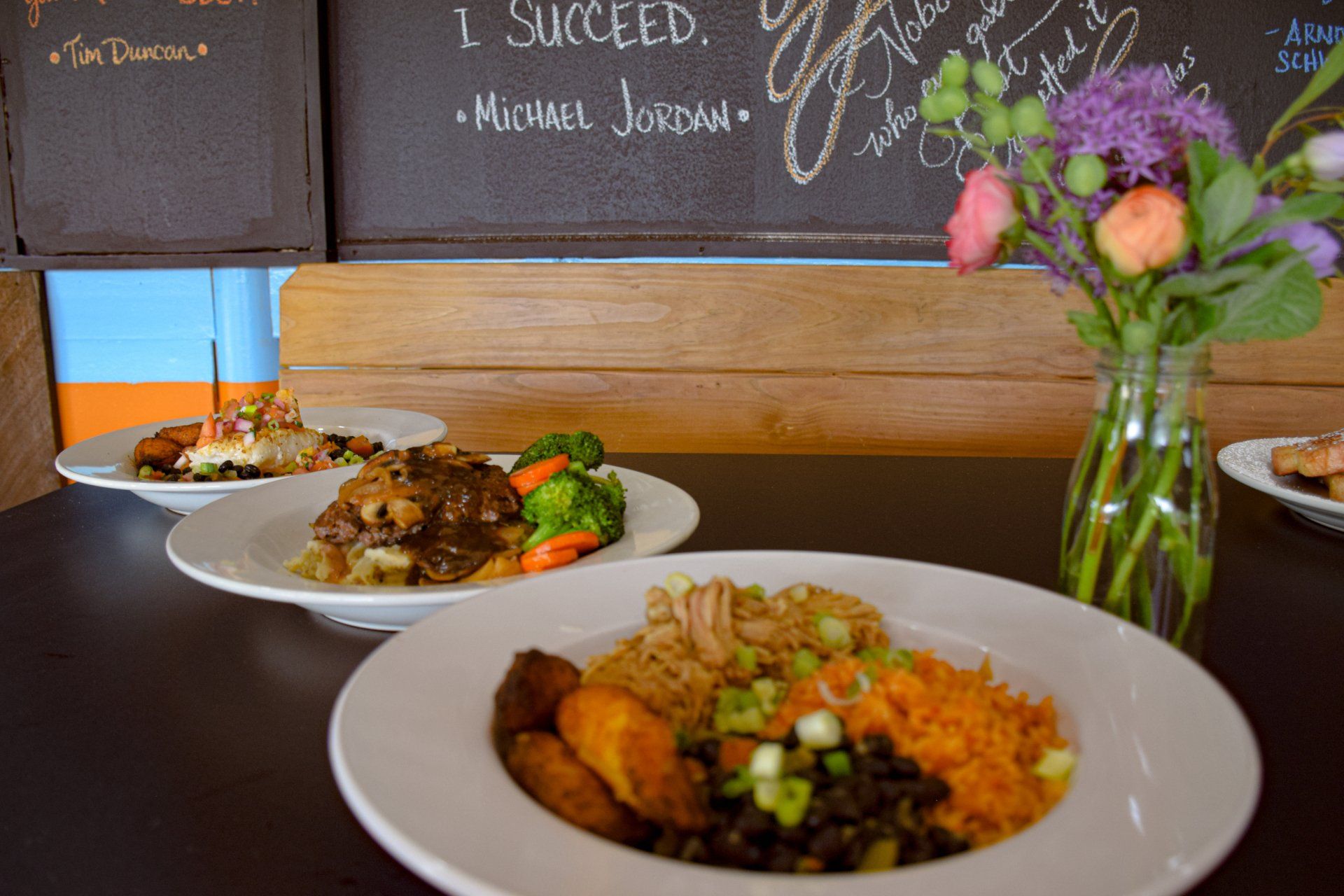 Three plates of food and a vase of flowers on a table