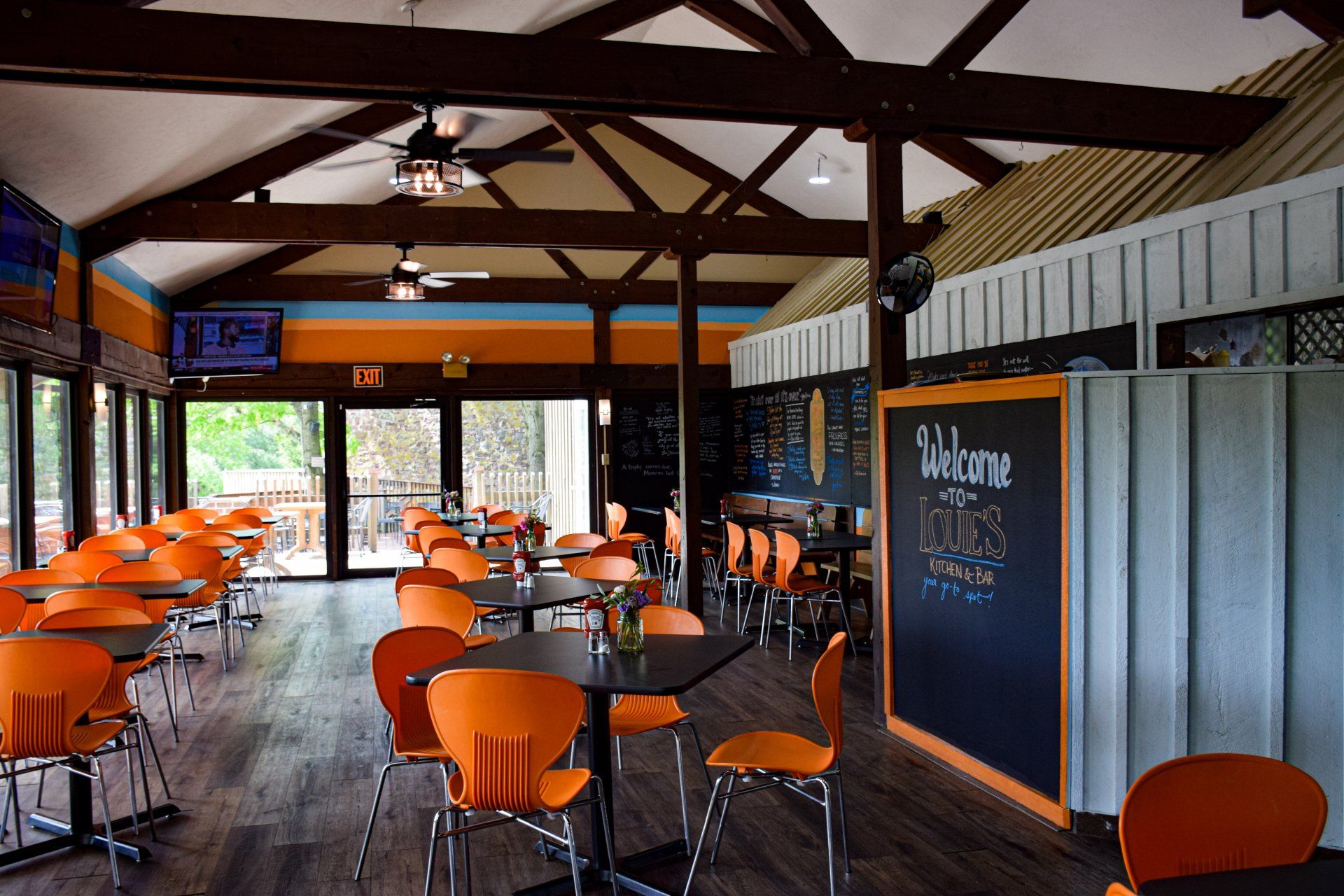 A restaurant with tables and chairs and a chalkboard that says welcome to the suns