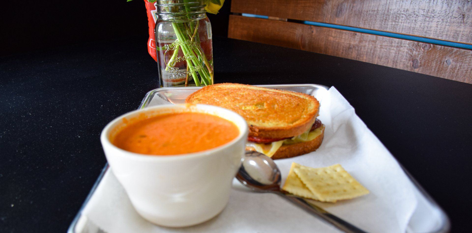 A bowl of soup and a grilled cheese sandwich on a tray