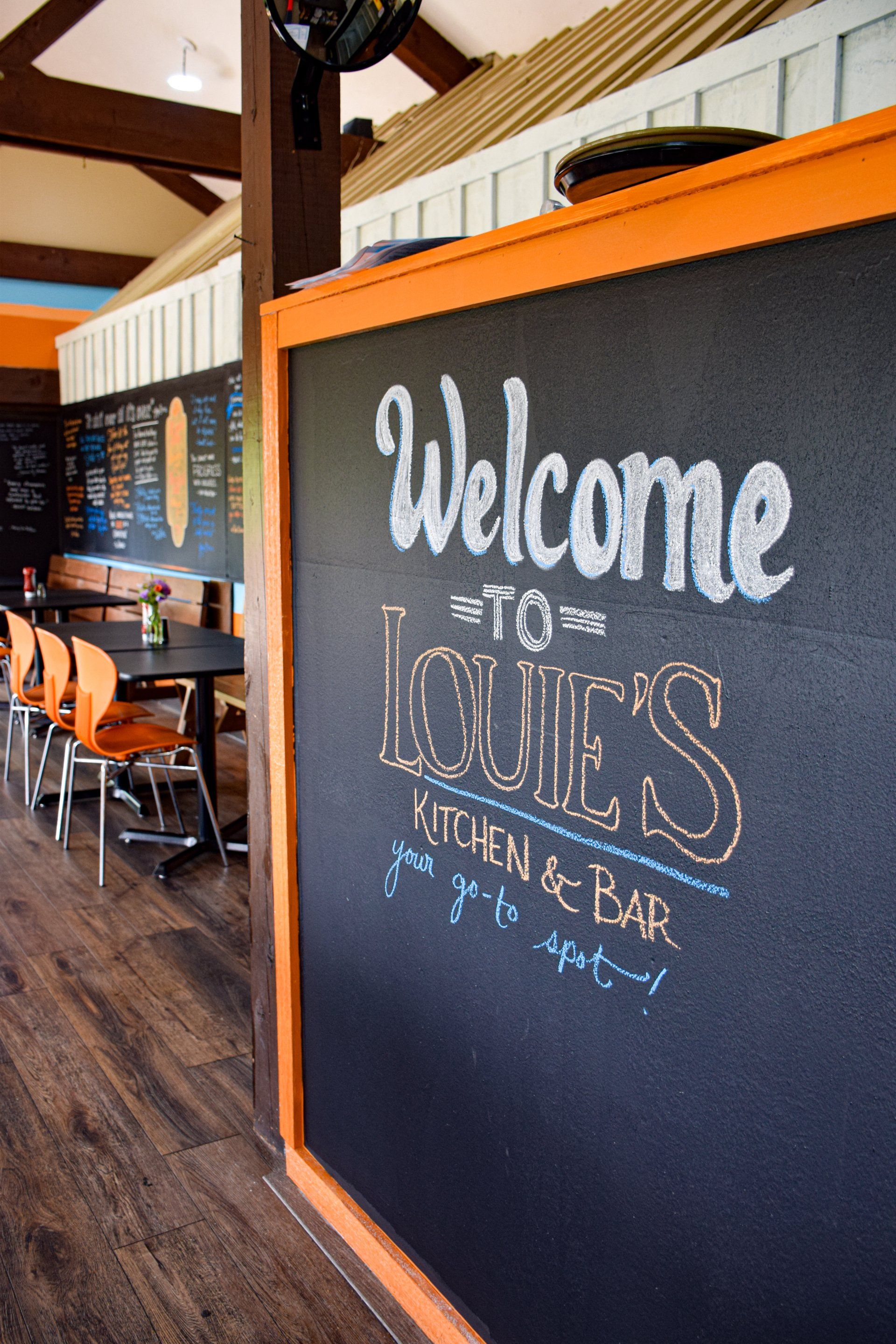A blackboard with the words welcome to louie 's kitchen and bar written on it
