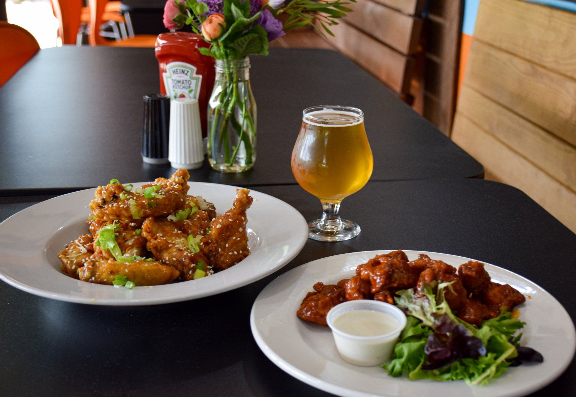 Two plates of food and a glass of beer on a table