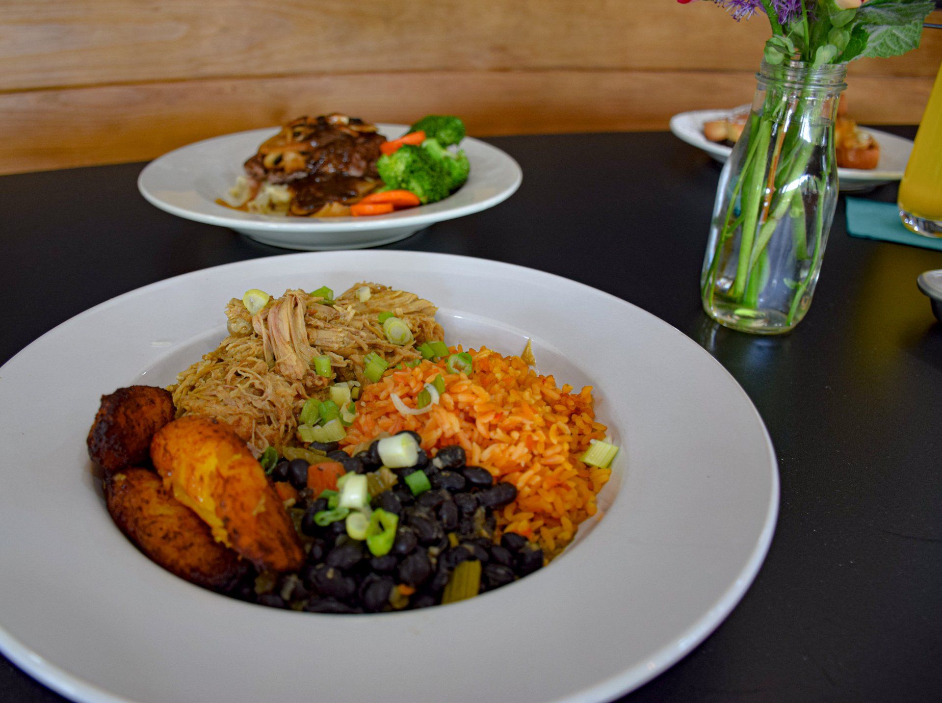 A plate of food on a table next to a vase of flowers