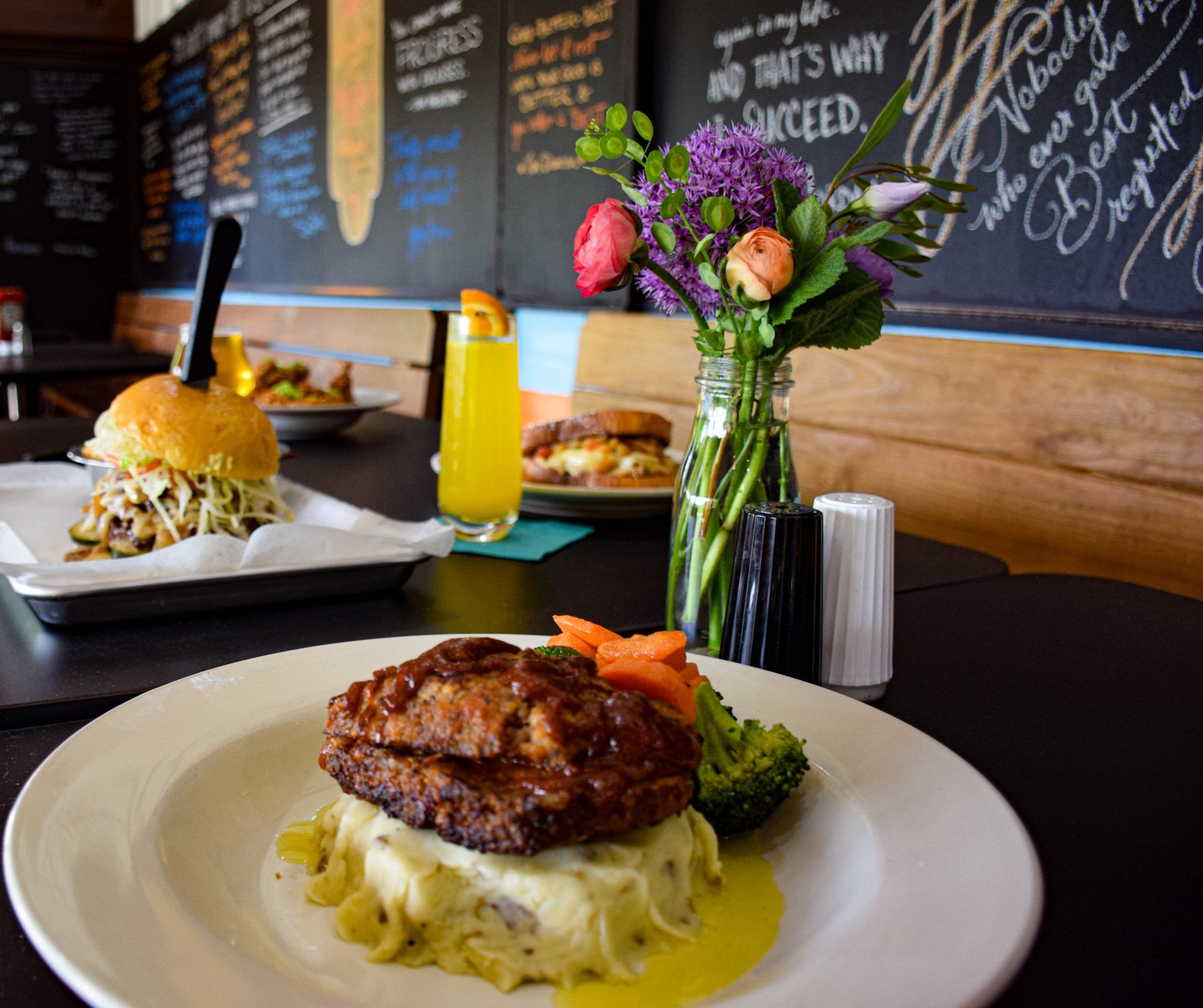 A plate of food sits on a table in front of a chalkboard that says