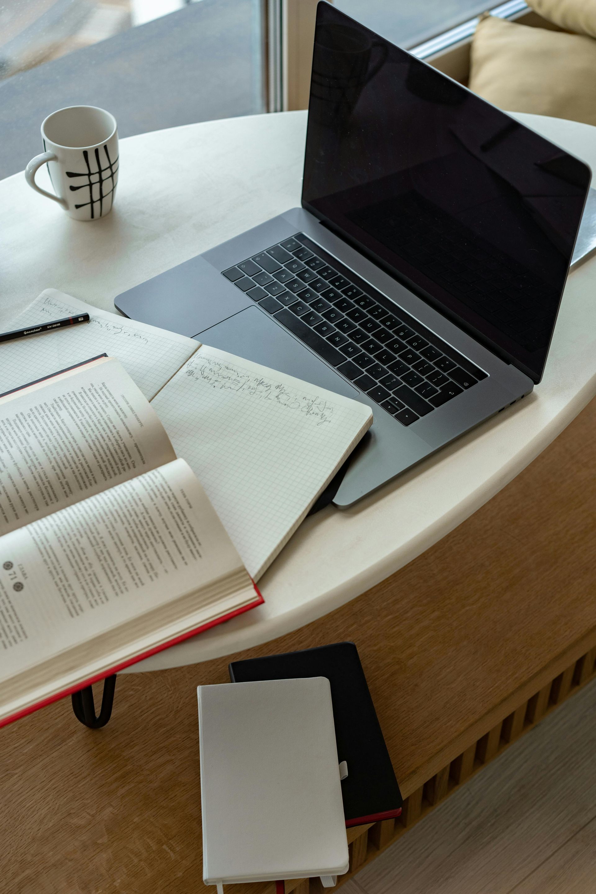 A laptop is sitting on a table next to a book and a cup of coffee.