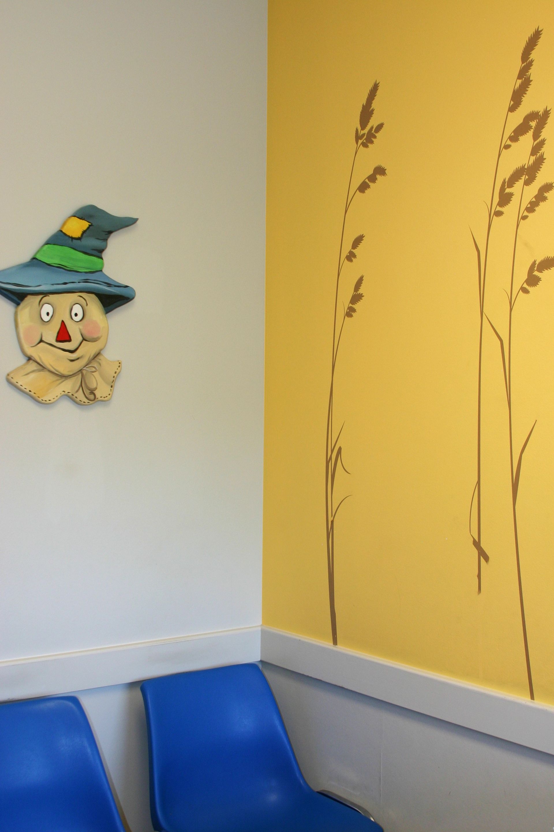 A scarecrow is hanging on a yellow wall next to blue chairs