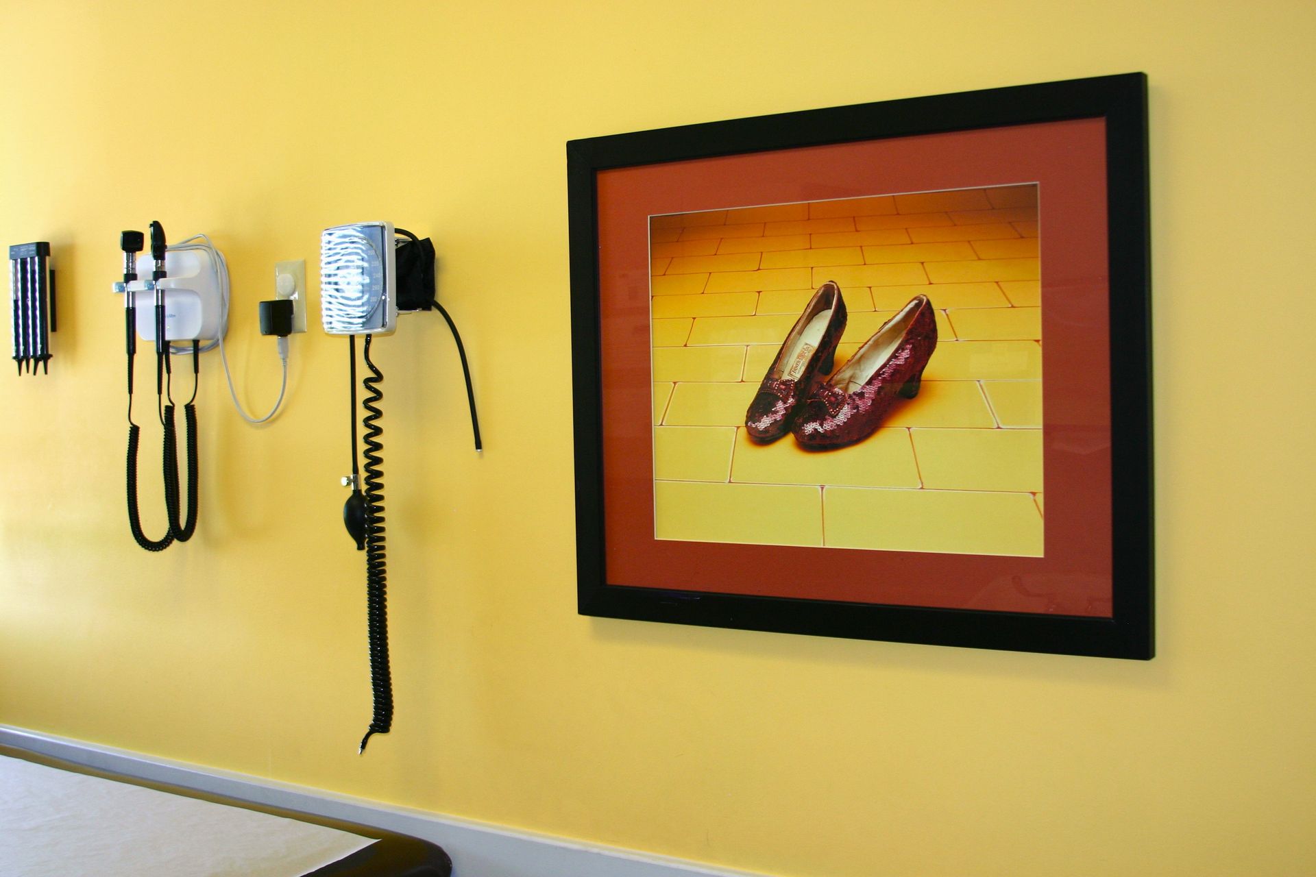 A picture of a pair of ruby slippers hangs on a yellow wall