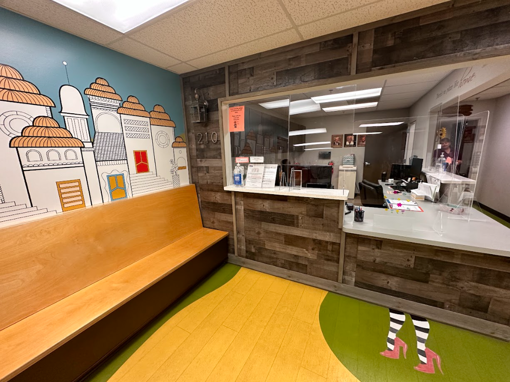 A waiting room with a wooden bench and a painting on the wall.