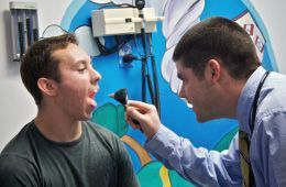 A doctor is examining a patient 's throat with a stethoscope.