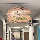 A wooden sign is hanging from the ceiling in a hallway.