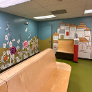 A waiting room with a wooden bench and a painting on the wall.