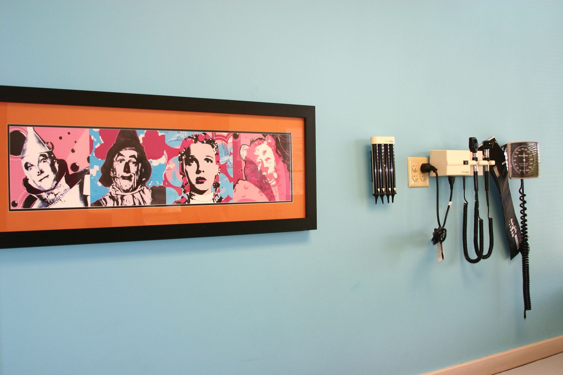 A framed picture hangs on a blue wall next to a stethoscope