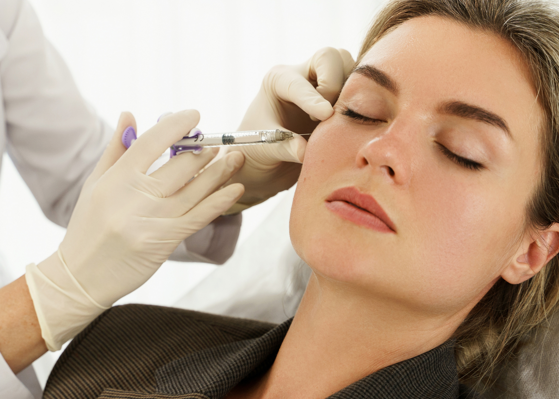 A woman is getting a botox injection in her face.