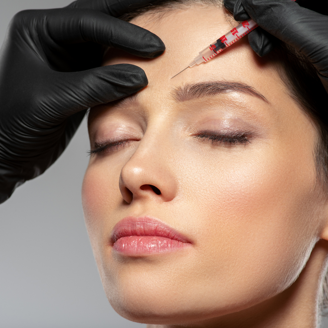 A woman is getting a botox injection in her forehead.