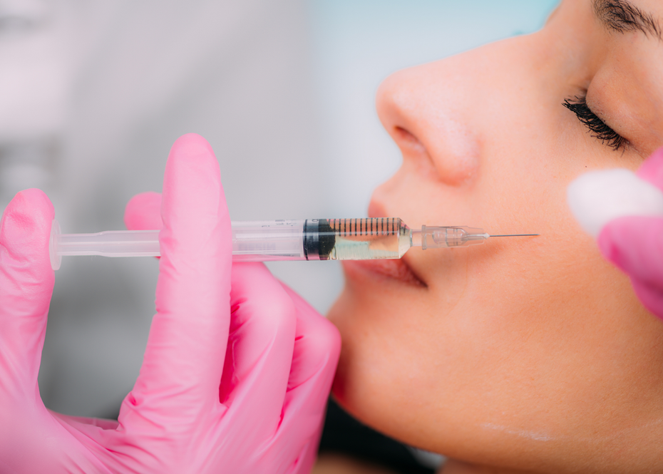 A woman is getting a botox injection in her lips.