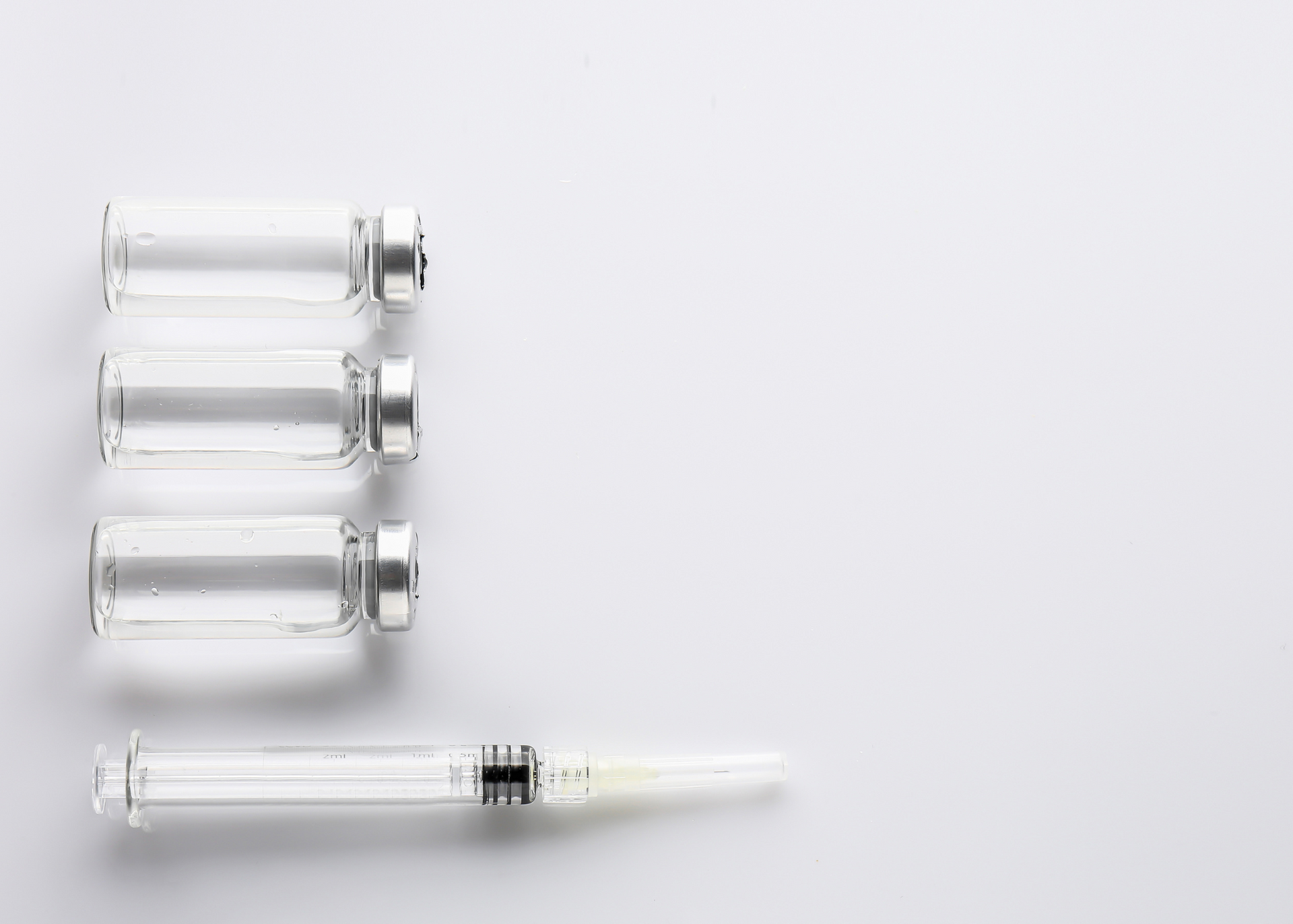 Three empty bottles and a syringe on a white background.