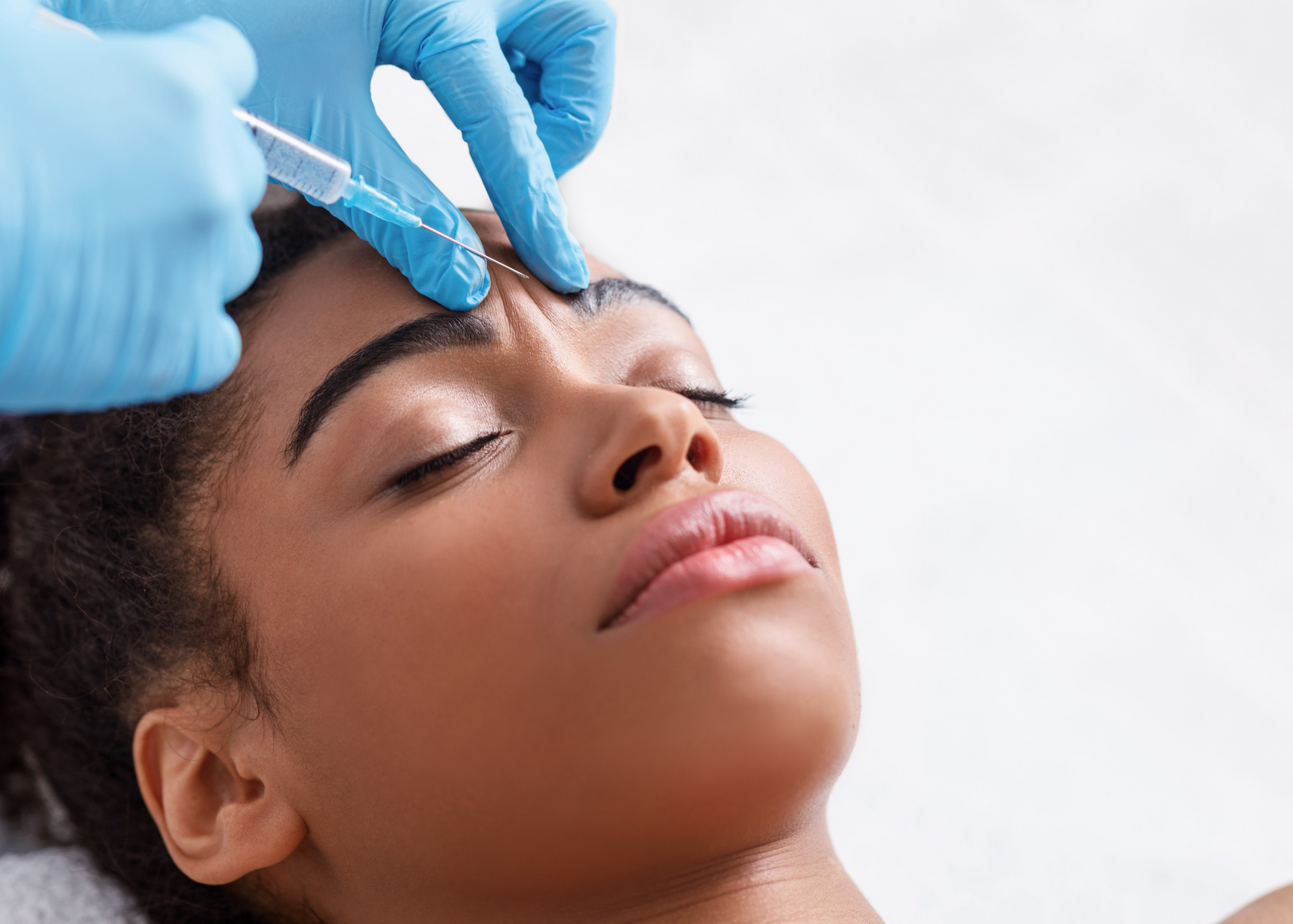 A woman is getting a botox injection in her forehead.