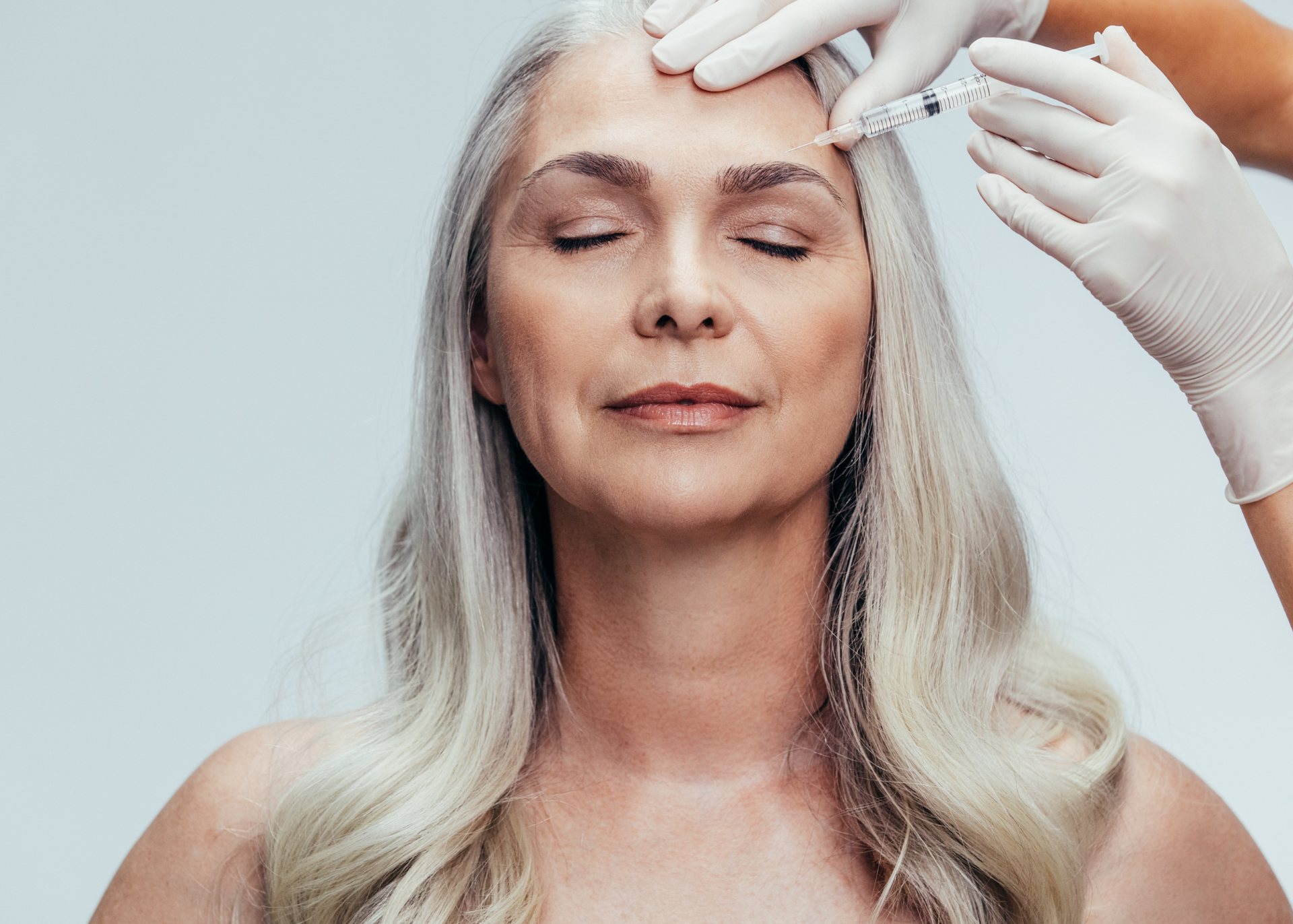 A woman is getting a botox injection in her forehead.