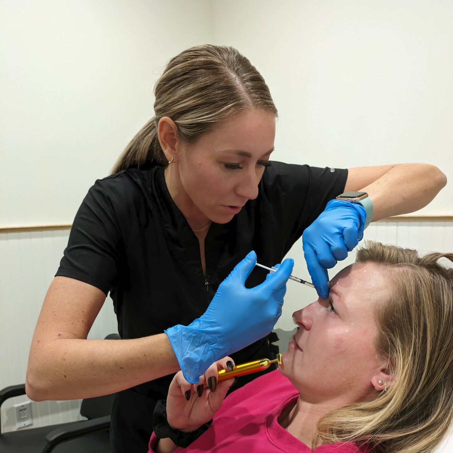 A woman wearing blue gloves is giving a woman an injection