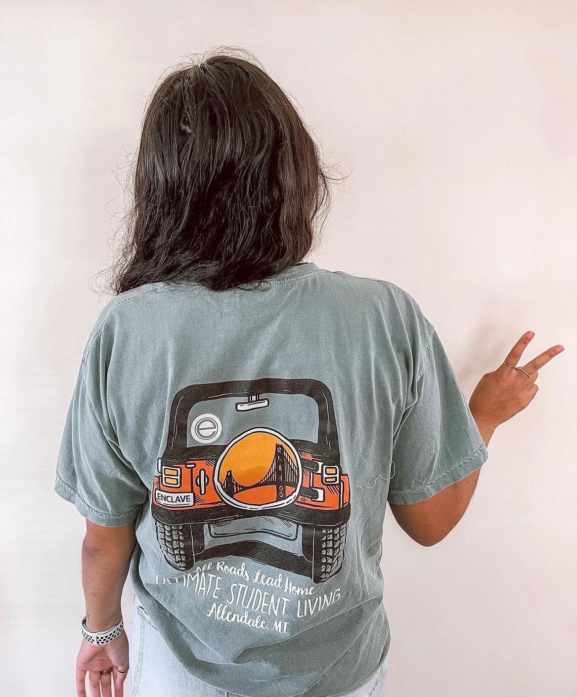 the back of a woman standing holding us a peace sign.