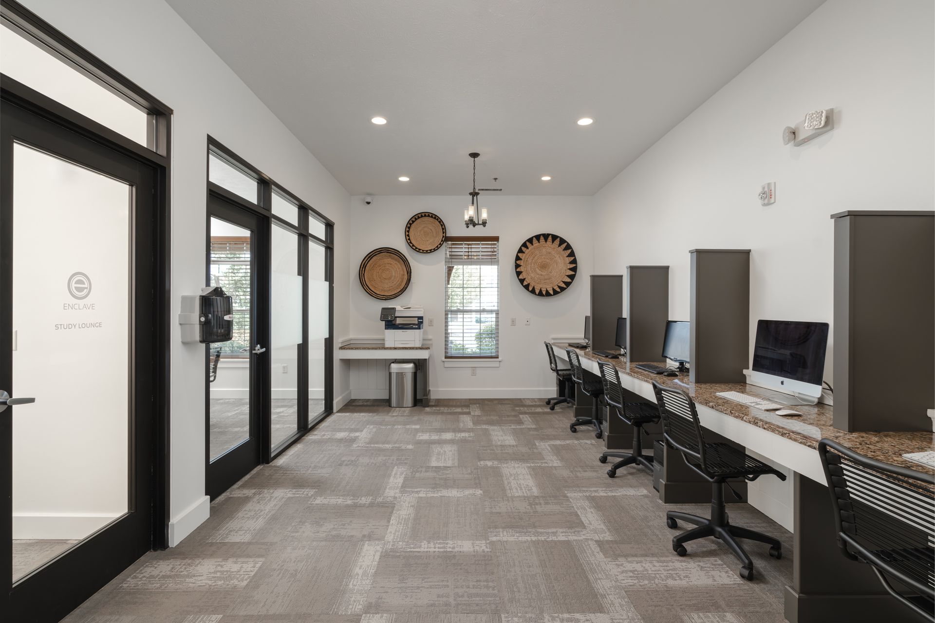 A computer lab with monitors, desks, chairs, and decorative wall hangings.
