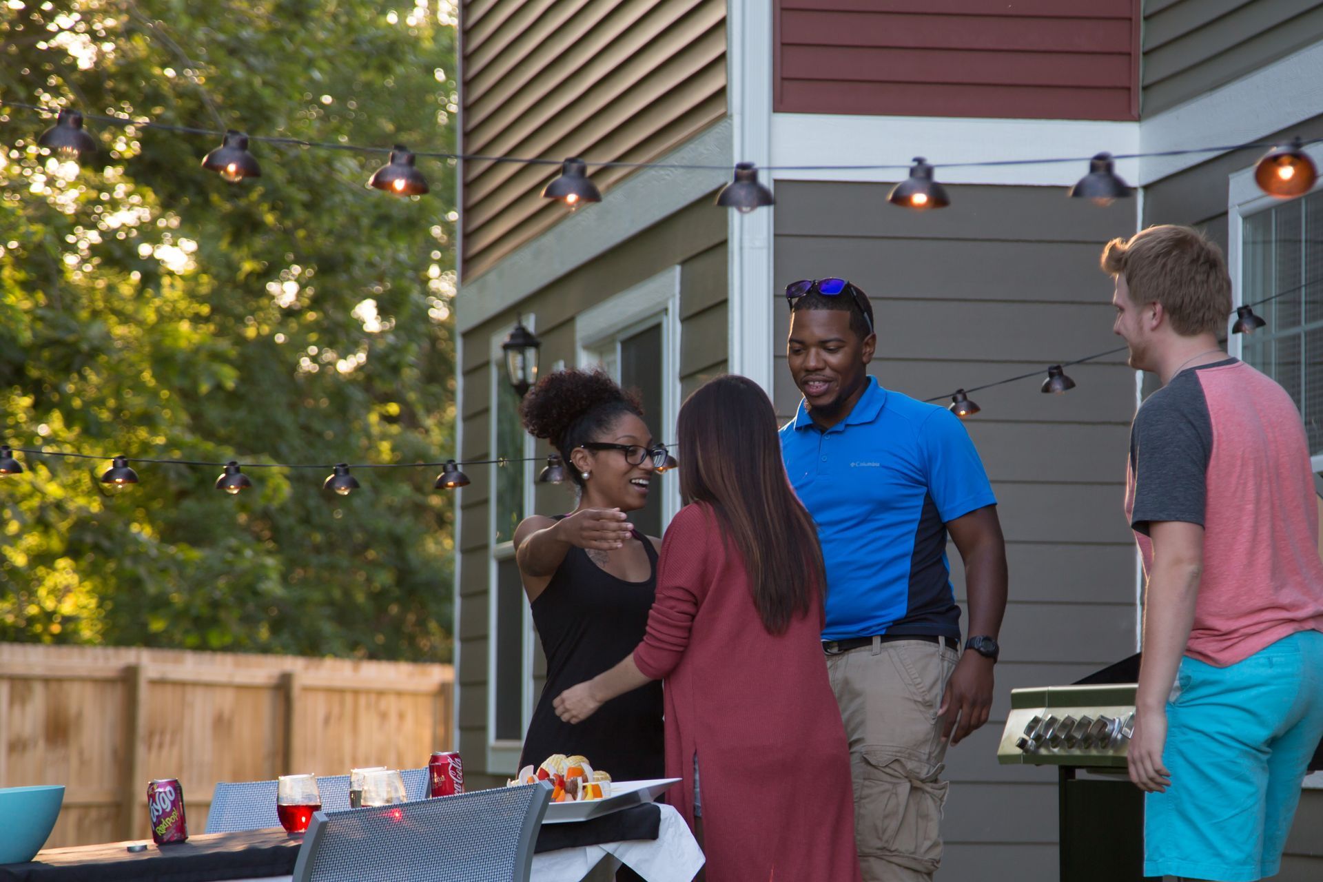 Four people greeting each other at a bbq event. 