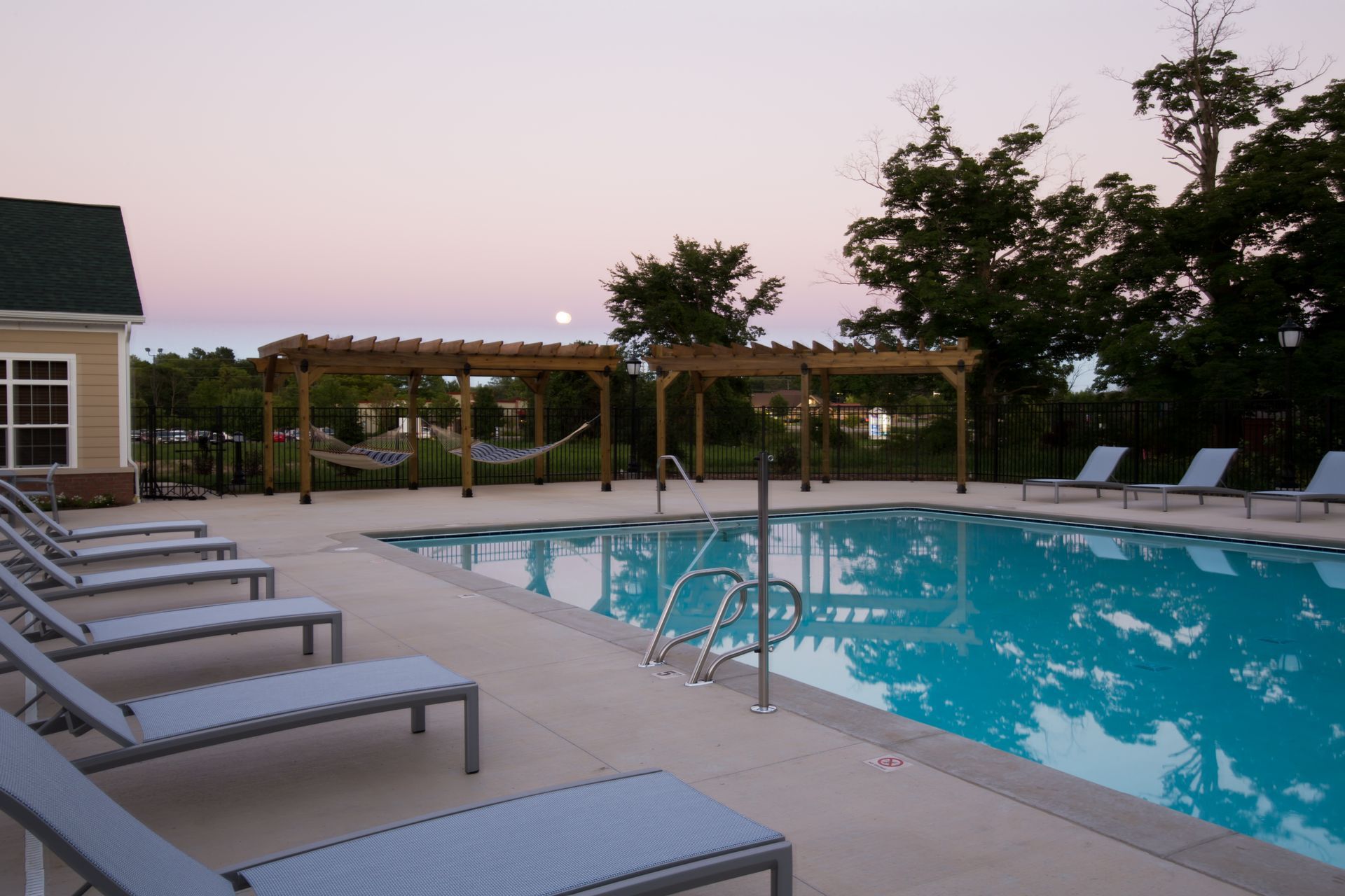 Community report style pool at dusk with moon in background