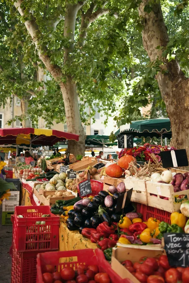 Outdoor farmers market with colorful produce displayed in crates.