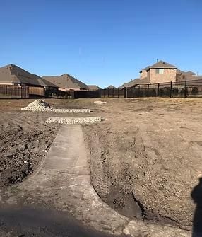 Dirt landscape with concrete paths and houses in the background.