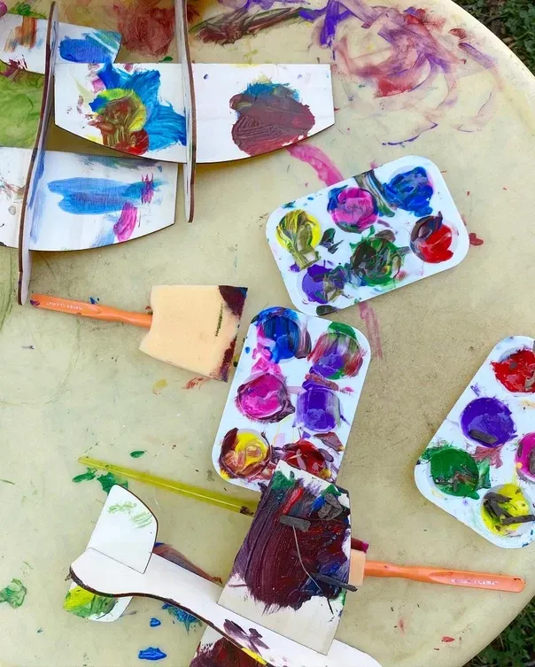 A bunch of paint brushes and palettes on a table