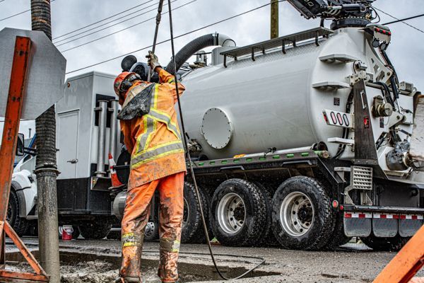 A man is standing in front of a vacuum truck.