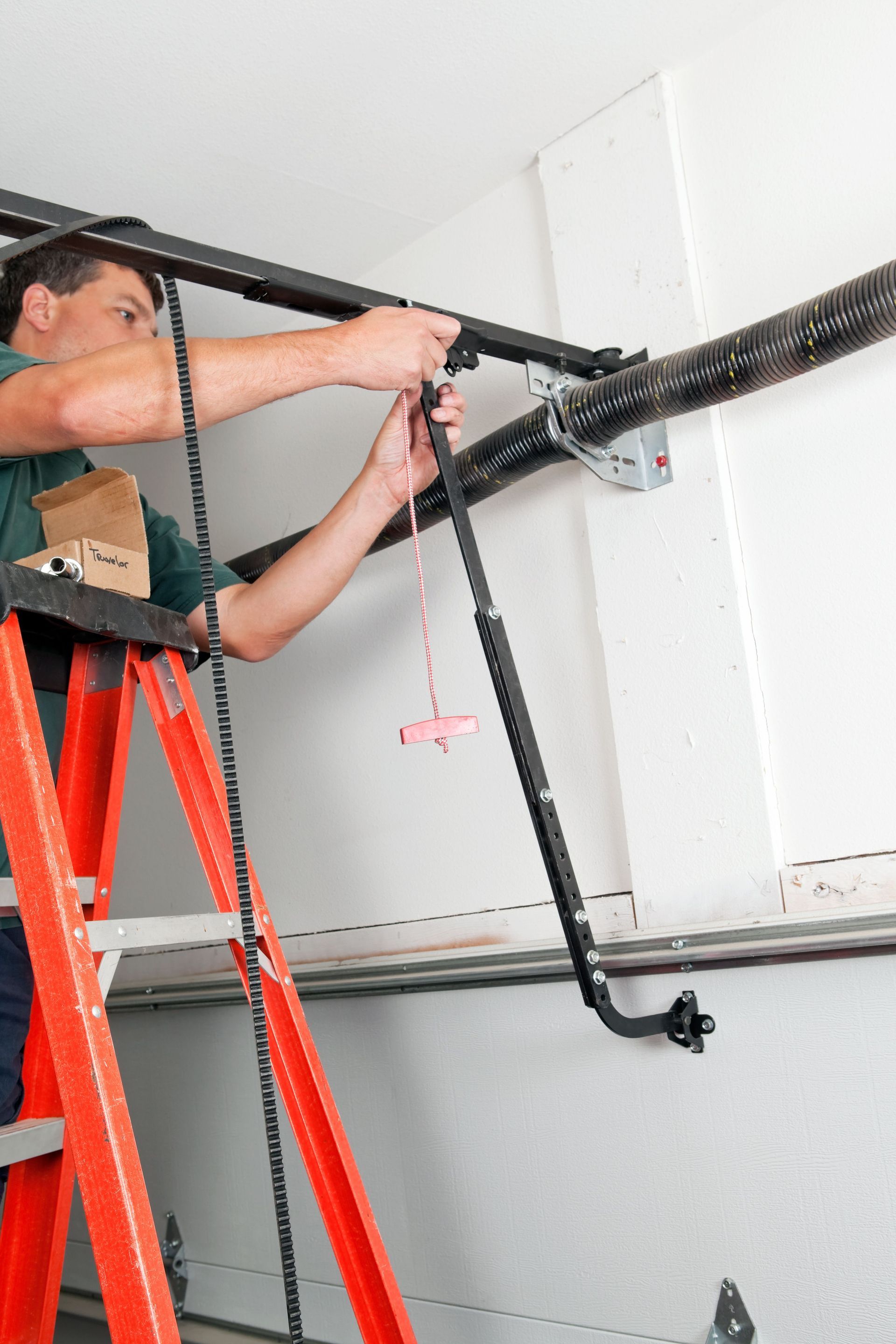 A man is standing on a ladder fixing a garage door