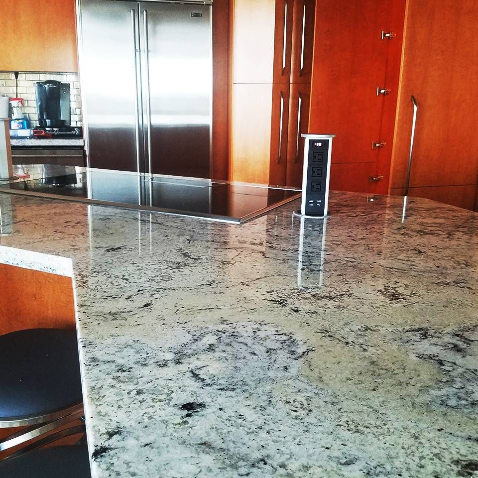 A kitchen with granite counter tops and a stainless steel refrigerator
